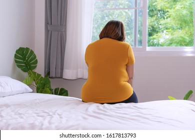 Overweight unhappy asian woman extra heavy body cellulite sitting on bed at home. Upset oversized lady worry diet weight loss suffering from extra weight. Obesity unhealthily concept. - Shutterstock ID 1617813793