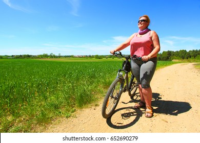 Overweight Woman And Bicycle. Active People Enjoying Summer Holidays On Countryside. 