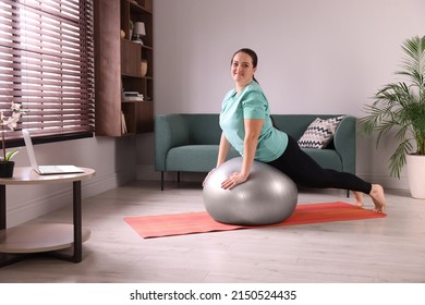 Overweight Woman Doing Exercise With Fitness Ball At Home