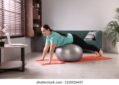 Overweight Woman Doing Exercise With Fitness Ball While Watching Online Class At Home