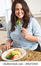 Overweight Woman Eating Healthy Meal In Kitchen