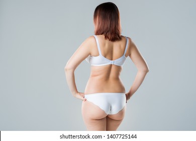Overweight woman with fat back and buttocks, obesity female body on gray background, studio shot