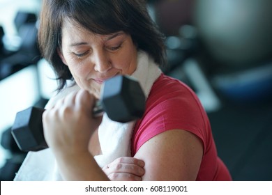 Overweight Woman At The Gym Lifting Dumbbells