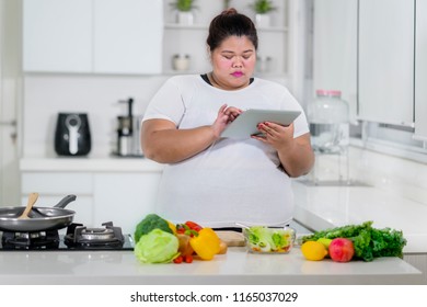 Overweight Woman Looking At Digital Tablet For Healthy Meal Recipe