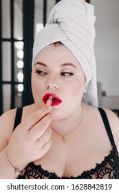 Overweight Woman Paint Lips With Cosmetic Lipstick Looking Away. Bath Towel On Lady Head After Shower And Wear Black Sexy Brassiere. Attractive Pretty Make Up Of Chubby Young Lady With Overweight