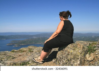 Overweight woman sitting on a mountain