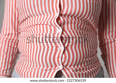 Overweight woman in tight shirt on grey background, closeup