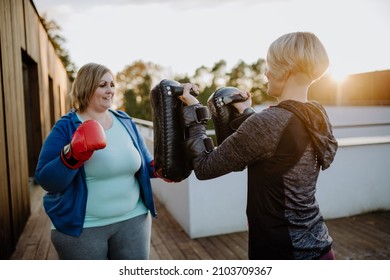 Overweight Woman Training Boxing With Personal Trainer Outdoors On Terrace.