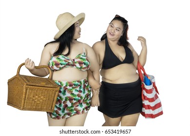 Overweight Women Walking While Carrying Picnic Basket And Beach Items, Isolated On White Background  