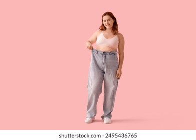 Overweight young happy woman in loose jeans on pink background. Weight gain concept - Powered by Shutterstock