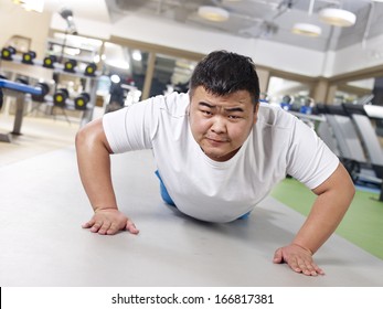 An Overweight Young Man Doing Push-ups With Sweating Face.