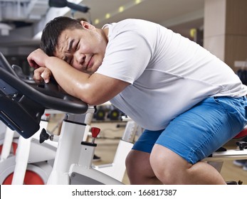 an overweight young man exhausted with exercising in fitness center.