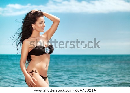 Overweight young woman in black swimsuit near the sea. Size plus or king size woman. Summer photo with copy space