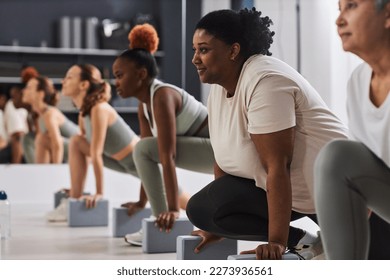 Overweight young woman exercising with other people in health club - Powered by Shutterstock