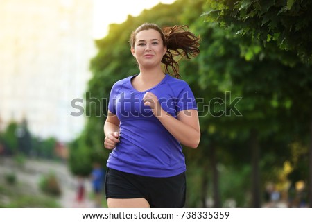 Overweight young woman jogging in the street. Weight loss concept