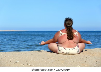 overweightl woman meditation on beach near sea
