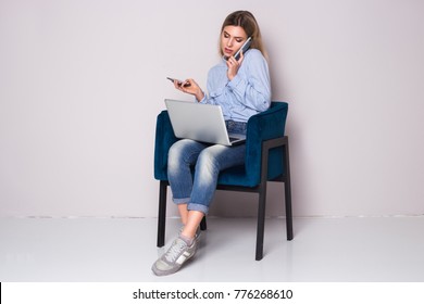 Overwhelmed Business Woman Sitting At Her Chair. Too Many Calls In One Day. Two Phones And Laptop. 