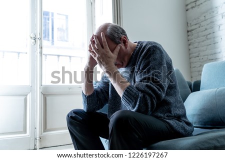 Overwhelmed old senior man suffering alone at home feeling confused sad alone on couch at home in Aging Retirement widower Dementia and Alzheimer concept.