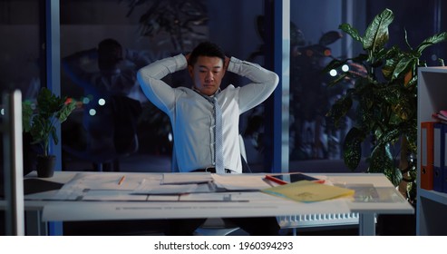 Overwhelmed Young Tired Asian Businessman Standing From Desk Leaving His Corporate Office Cabinet Late At Night. Concept For Workaholic, Exhaustion.