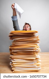 Overworked Businessman Sitting At His Desk Waving A White Flag Of Surrender Above A Big Pile Of File Folders