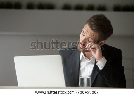Overworked businessman in suit tired from laptop work, exhausted man feeling lack of sleep, headache or eye strain at workplace, office worker suffering from chronic fatigue after long using computer