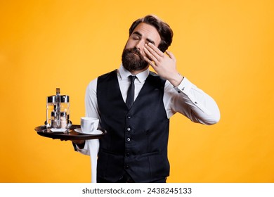 Overworked butler stretching in studio, feeling exhausted after long busy day at restaurant. Professional stylish waiter falling asleep and suffering from burnout, feeling sleepy on camera.