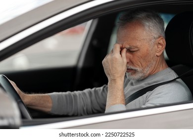 Overworked elderly Caucasian man 60-70 years old, taxi driver feeling headache and tired, stopping after driving a car in a traffic jam. Close-up of an exhausted senior male driver - Powered by Shutterstock