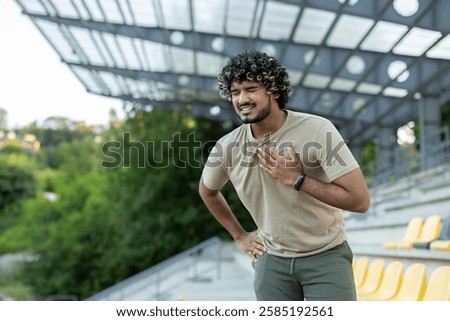 Overworked and overtired runner while doing active physical exercise and running outside in the fresh air, man holding hand on chest, severe heart pain, heart attack.