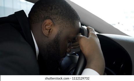 Overworked personal driver falling asleep on steering wheel of car, tired man