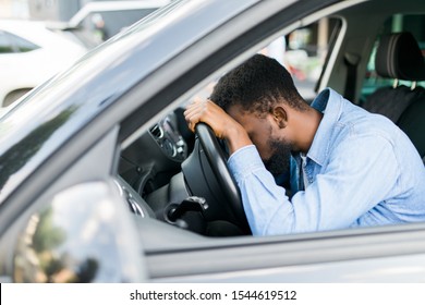 Overworked personal driver falling asleep on steering wheel of car, tired man