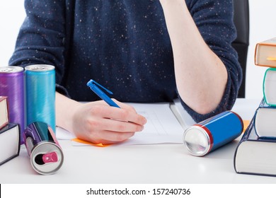 Overworked student with empty cans writing the notes