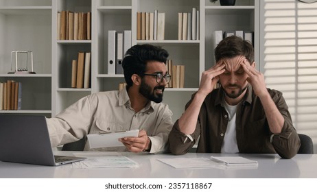 Overworked tired sick man suffer headache ignoring obsessive annoying colleague disturb talk smile discuss project with laptop two multiethnic businessmen diverse men solve teamwork problem in office - Shutterstock ID 2357118867
