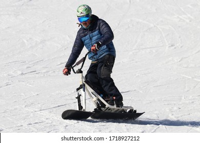 "Ovindoli, L'Aquila - March 8 2018" man snowboarder during the descent on the ski slope snow scoot ski bike, Oakley mask, Burton AK jacket, Neff gloves on mountain background