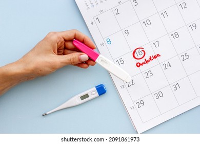 Ovulation home test in female hand over calendar with red mark - Shutterstock ID 2091861973