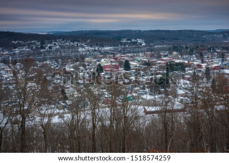 Owego is a small village in New York State, located along the Susquehanna River, photographed from the top of a hill during a winter morning with fresh snow on rooftops . 