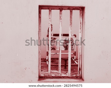 An owl perched inside a barred window cage in red monochrome tone.Taken In Malang, East Java, Indonesia On August 09 2026