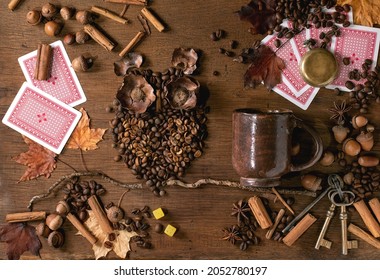 Owl shape from coffee beans and spices. Owl sit on the branch with coffee cup, playing cards, dice over wooden background. Funny mystery coffee prediction concept