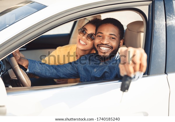 Own Auto. African
American Spouses Showing New Car Key To Camera Sitting In
Automobile. Selective Focus