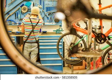 Owner Bike Mechanic Preparing Racing Bicycles In Workshop - Young Trendy Man Checking New Carbon Fiber Superbikes Indoor - Professional Maintenance Concept -  Focus On Guy - Warm Filter