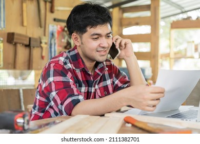 Owner Entrepreneur Startup Small Shop Business. Carpenter Asian Young Man Using Smartphone, Mobile Talk With Client About Order, Use Laptop Computer For Marketing Online. Factory Industry Of Wood.