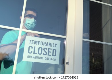 Owner of establishment glues a sign with the inscription TEMPORALLY CLOSED during coronavirus pandemic. Private business closes from the quarantine COVID-19 pandemic. Caption: temporarily closed.