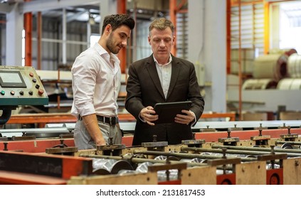 The owner of the factory holds the tablet, consults with the production control staff, consults on the development of quality steel plate products, stands and talks at the factory.