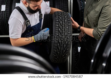 owner garage shop holding best tire in a supermarket mall, measuring rubber car wheel. at work place
