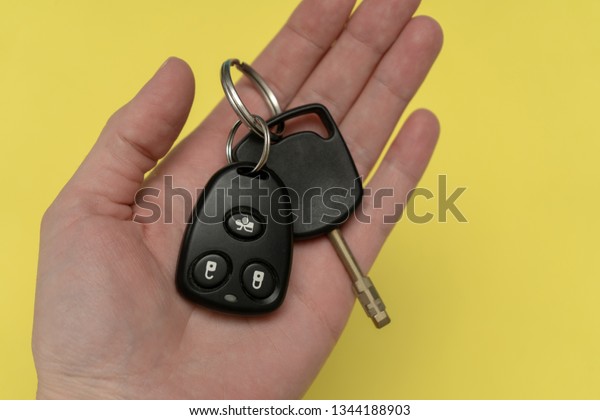 Owner holding auto key and remote above the\
yellow background. Success in\
business