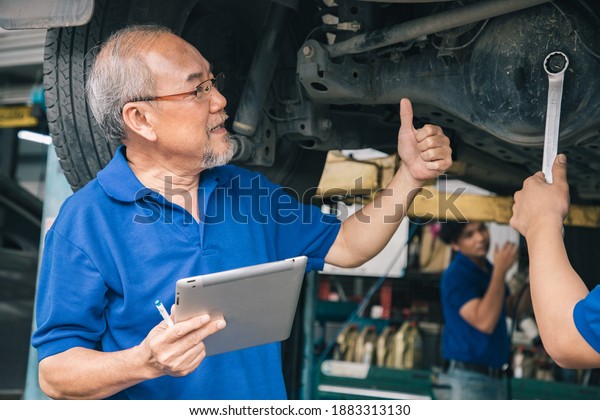 Owner and Service staff man used tablet for
repair and fixed machine in a garage store. They was worried about
choosing axle or suspension of the
car.
