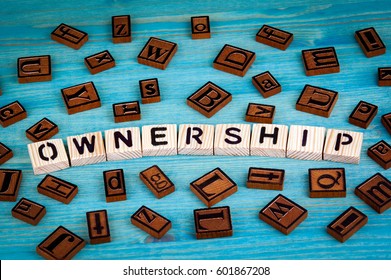 ownership word written on wood block. Wooden alphabet on a blue background