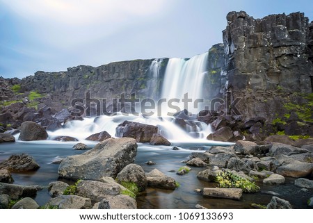 Oxararfoss waterfall in Thingvellir plain of Parliament, Golden Circle, Iceland. Landscape picture of huge waterfall in icelandic national park with nice boulders in the front of photo.