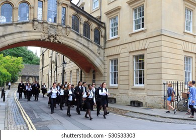 OXFORD - JUL 11, 2014 : Graduates of Oxford University walk by Hertford College, wearing traditional academic gowns.