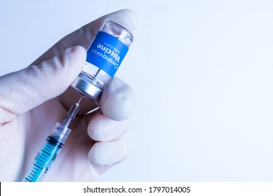 Oxford vaccine - Coronavirus Vaccine - Doctor with surgical glove holding a vaccine vial with the blue label written Coronavirus Vaccine - Sars-Cov-2 over white background