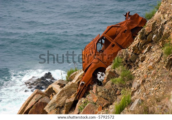 oxidized rest of a car left\
in a cliff
